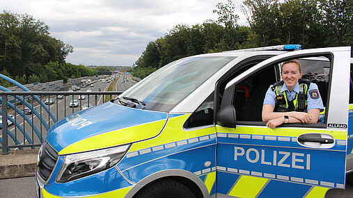 Foto zum Thema "Wie wird man Polizist*in": Zu sehen ist Svenja, die in der Tür des Streifenwagens steht.