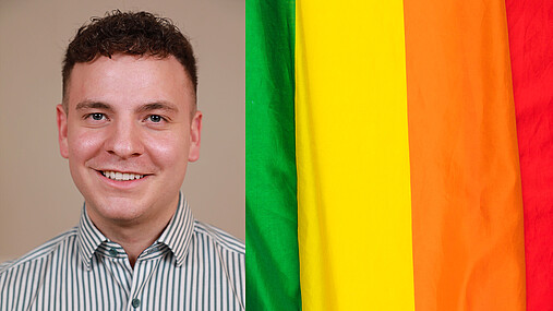 Das Foto zeigt Alexander Seeger, Mitglied der AG Diversity der dbb jugend, neben einer Regenbogenflagge.