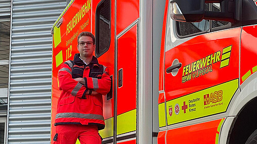 Foto zum Thema Ausbildung zum Notfallsanitäter: Zu sehen ist Tim, einen Notfallsanitäter aus Wuppertal, vor dem Rettungswagen.