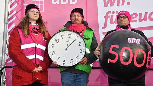 Das Foto zeigt drei Gewerkschafter, die mittlere Person hat eine Uhr in der Hand, es ist fünf  nach zwölf für den öffentlichen Dienst.