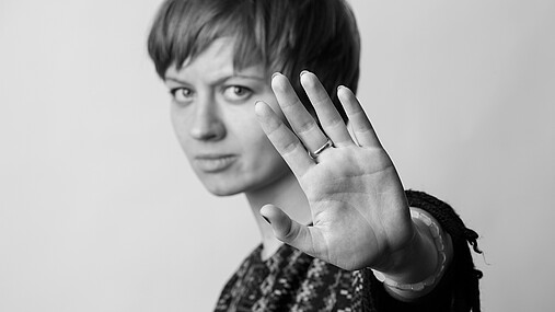 Foto zum Thema Gewalt gegen Frauen: Zu sehen ist eine Frau, die ihre Hand hebt und damit STOP symbolisiert.