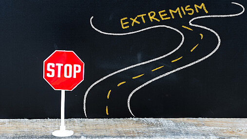 Foto zum Thema "was tun gegen Extremismus": Zu sehen ist eine Straße, an deren Ende "Extremismus" steht, davor ein Stop-Schild.
