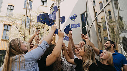Das Foto zeigt Mitglieder der dbb jugend, die europäische Fahnen schwingen.